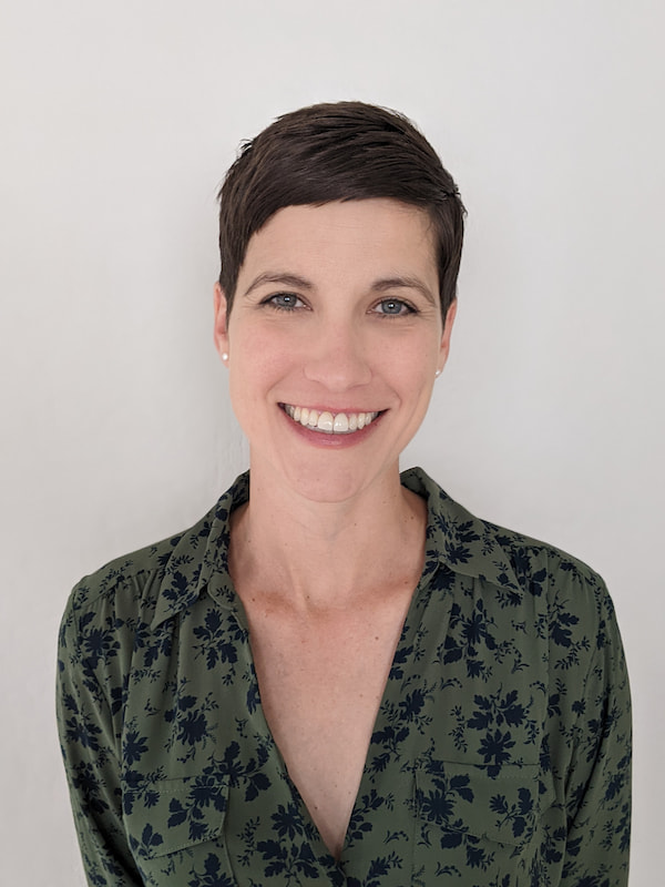 White woman with pixie-style brown hair smiling